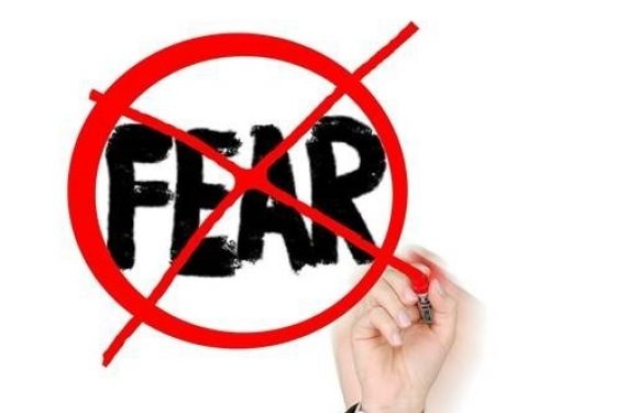 Hand writing crossing out the word fear on a marker board