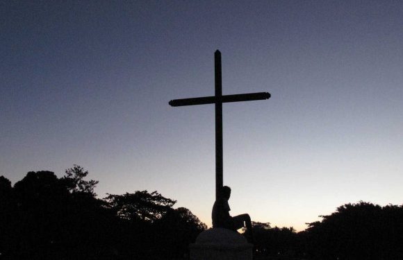 Cross with a person sitting at the foot of the cross
