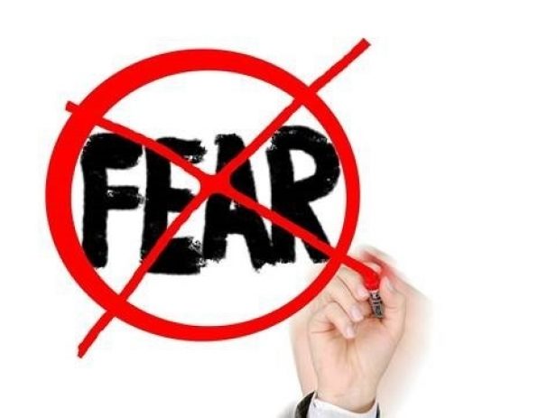 Hand writing crossing out the word fear on a marker board