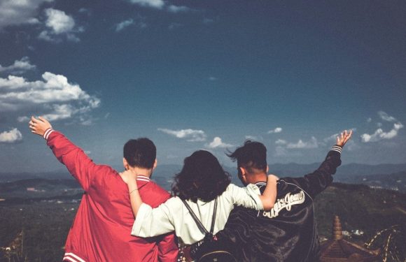 Three friends joyously looking over a hillside