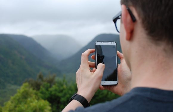 Person taking picture of mountains with cell phone